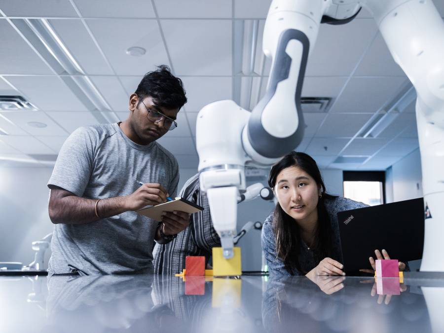 Students looking at a robotic arm.